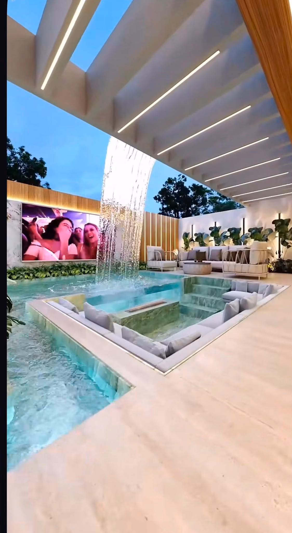 Cascada junto a la piscina y el porche chill-out de la vivienda al atardecer
