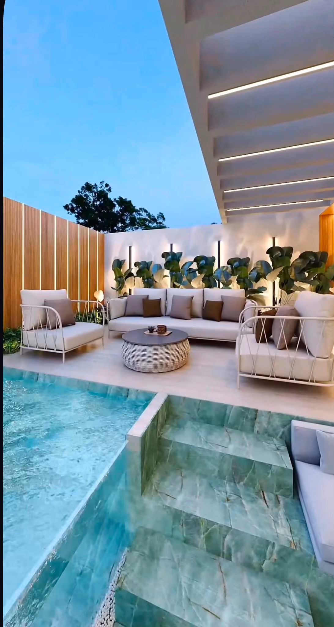 Zona chill-out junto a piscina con escalera revestida en ónice verde e iluminación integrada al anochecer