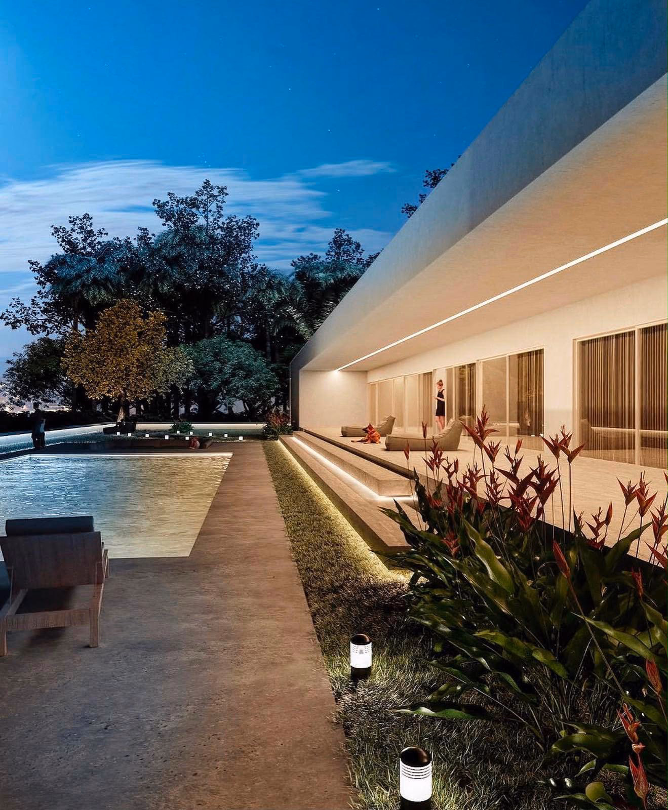 Piscina y porche de vivienda unifamiliar iluminados al anochecer, con jardín tropical