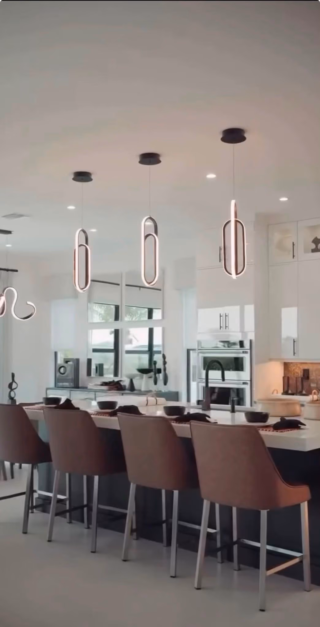 Cocina con isla en negro y lámparas ovaladas